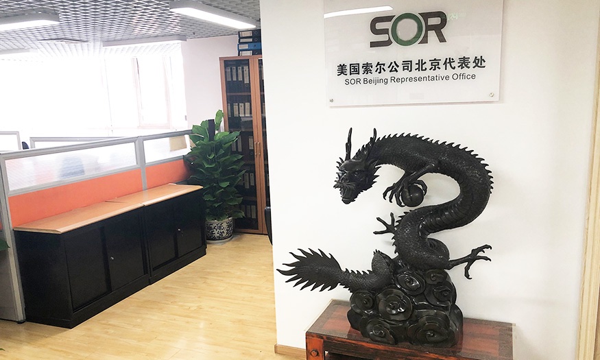 Indoor sign at the SOR Beijing Representative Office with a dragon statue on stand beneath it